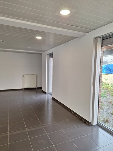 Photo avant transformation de l'espace central avec des murs blanc et deux baies vitrées