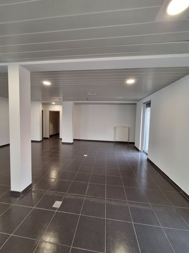 Photo de l'espace central avant transformation avec du carrelage gris anthracite et des murs blanc