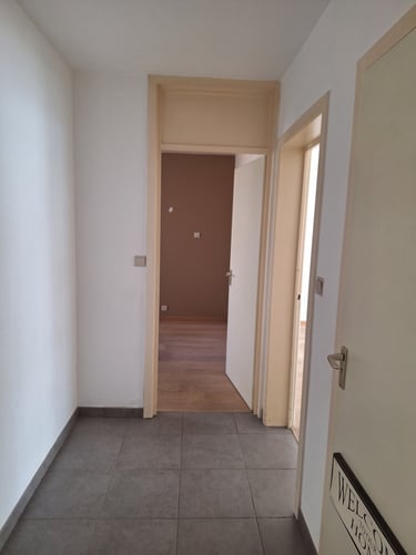Vue d'un couloir avec des portes beiges avant transformation