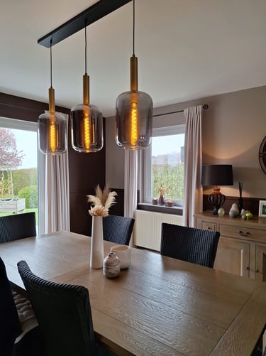 Une salle à manger dans les tons de beige et brun avec un luminaire à trois globes