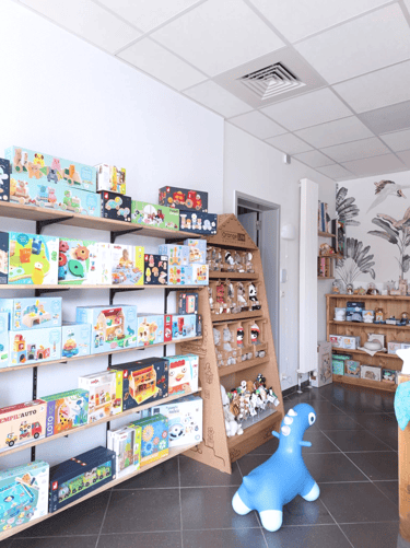Magasin de jouets avec des étagères en bois et du papier peint fleuri
