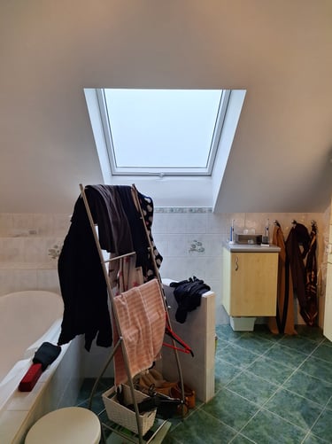 Salle de bain avant rénovation avec un velux, une baignoire et des meubles