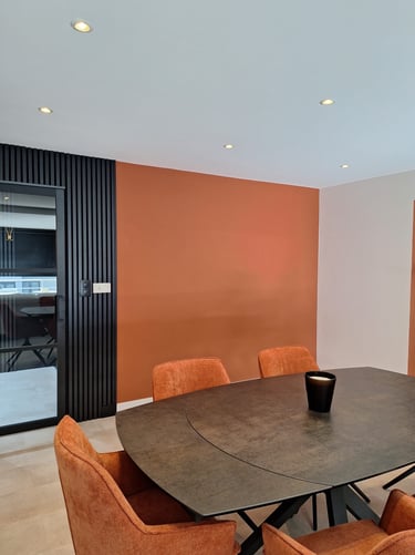 Table de salle à manger avec chaises terracotta mur terracotta et lattes de bois noir avec verrière