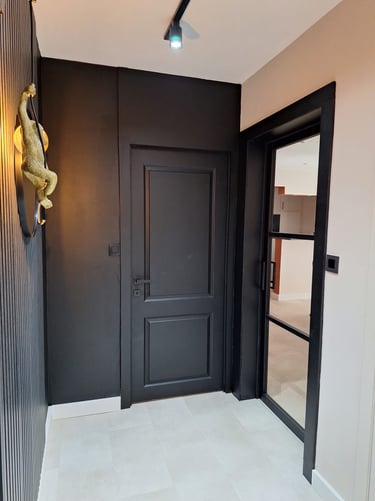 Un hall d'entrée noir et beige avec des lattes de bois et un verrière noire