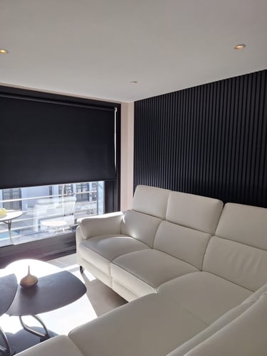 Image d'un canapé blanc devant des lattes de bois noires des stores noirs et une table basse