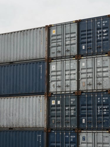 Close-up of organized shipping containers stacked neatly at a cargo terminal, desaturated steel and navy tones, 35mm
