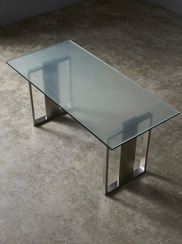 Overhead flat-lay of a rectangular dining table with a tempered-glass top and powder-coated steel base, even north-facing studio light, no props, concrete floor visible beneath