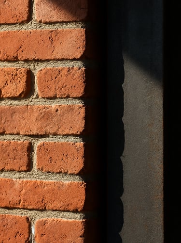 Detail shot of architectural material transition, raw handmade red brick meeting a dark structural steel column, sharp shadows, natural side lighting.