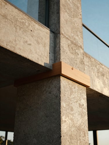 Close-up of raw concrete and oak wood joins in a modern coastal interior, warm low-angle light.