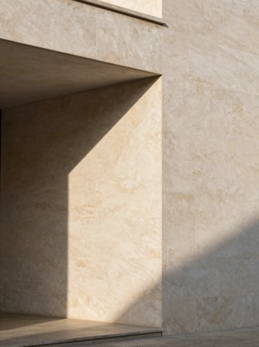 Minimalist Portuguese architecture, clean limestone facade with sharp geometric afternoon shadows, soft warm-toned stone texture, editorial framing.