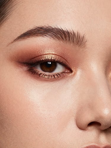Close-up of model's radiant eyes with warm bronze and gold eyeshadow, soft diffused key lights, professional makeup artistry