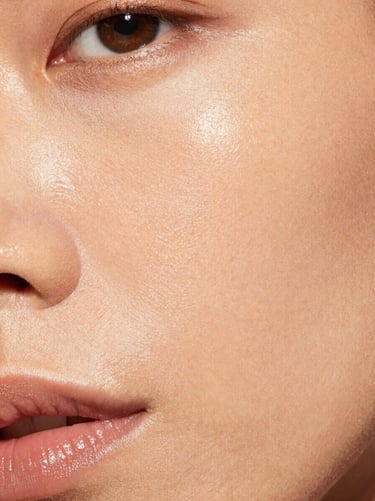 High-contrast macro portrait showing flawless foundation coverage on textured skin, warm lighting, showing real pores and luminous finish