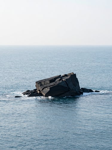 A wide minimalist coastal landscape, featuring a single dark rock formation emerging from a pale ice blue ocean, soft natural lighting, serene atmosphere, high-resolution photography, International / Western.