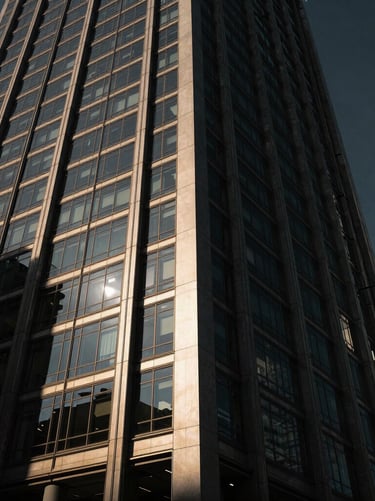 Low-angle heroic architectural shot of a modern glass-and-steel office tower in Singapore, sharp sunlight hitting the facade, dramatic low-key shadows, Hasselblad medium format