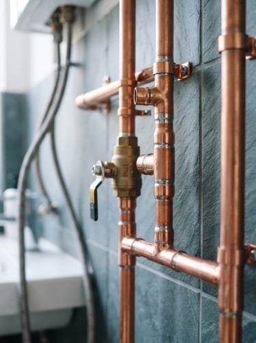 Close-up of clean modern copper pipework with neat solder joints in a bright residential utility room, natural daylight, cool slate tones