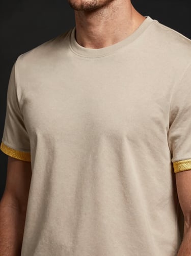 Close-up of a premium gold-accented beige t-shirt on a model, warm directional lighting, high-end casual wear, 85mm lens