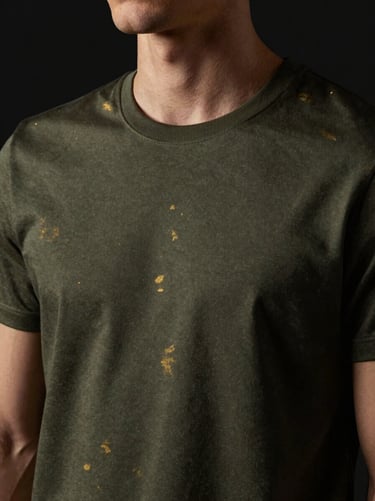 Close-up of a premium dark olive green t-shirt on a model, moody directional lighting with subtle gold highlights, 85mm lens
