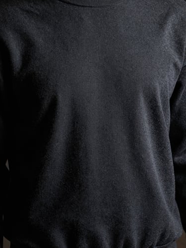 Low-key directional lighting highlighting the textured surface of a thick screen-printed graphic on a premium dark slate cotton sweatshirt.