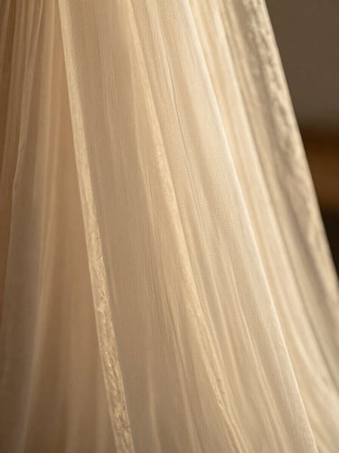 Tight macro shot of sheer voile fabric weave, translucent threads catching warm afternoon light, fine texture visible, warm cream tones, no people