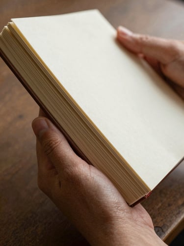 Extreme close-up of hands holding a physical, heavy-paper art journal, warm-toned, soft focus.