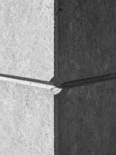 Macro shot of a concrete joint with hard directional lighting, sharp shadows, orthographic framing, high-contrast black-and-white.