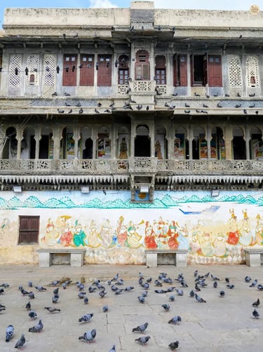 Lakeside steps of Gangaur Ghat with pigeons flying and havelis behind, udaipur Rajasthan.
