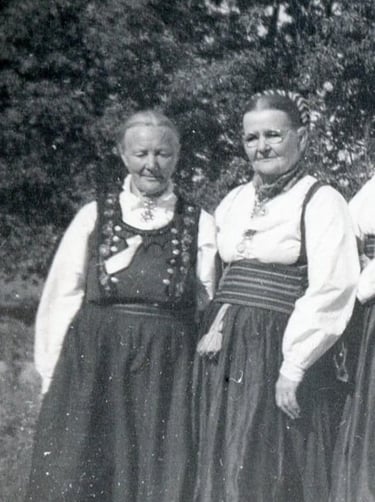 a black and white image of two women in bunad