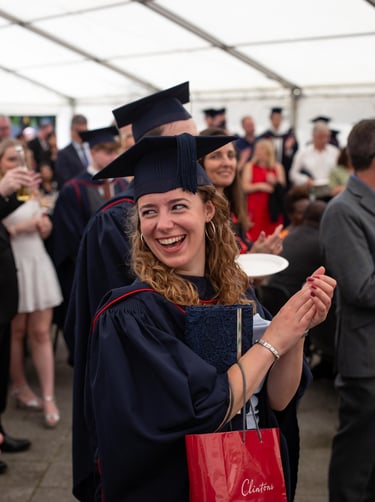Graduation event photo of a smiling graduate in cap and gown