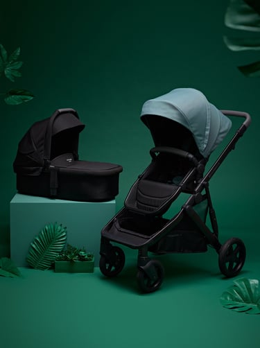 Product campaign photography - a baby stroller with a baby carriage in a green background