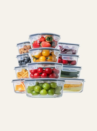 Stacked glass food storage containers with airtight lids filled with fresh fruits and vegetables.