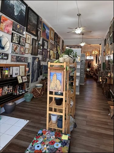 Interior of a local art gallery, The Collective, featuring paintings on walls and handmade pottery o
