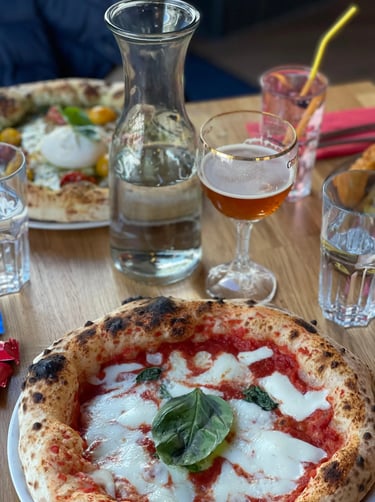Pizza margherita napolitaine servie à table avec basilic frais au restaurant Histoire sans Faim à Lausanne, ambiance