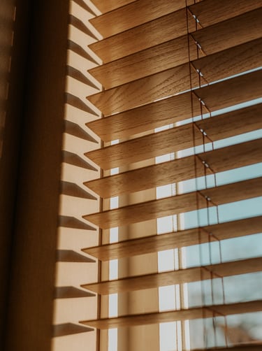 Natural wood horizontal window blinds with sunlight filtering through for home decor.