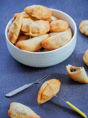 Zdjela puna punjenih piroga servirana na plavom stolnjaku.