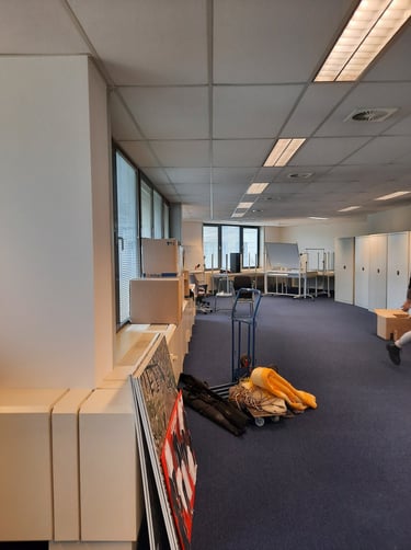 Espace vide avant transformation en bureaux avec de grandes baies vitrées et du mobilier.