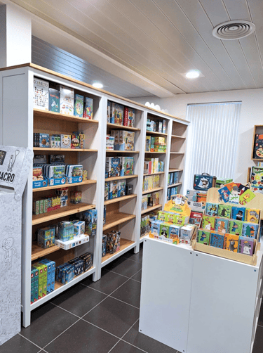 Aménagement du magasin de jouets avec des étagères blanches et un plan de travail comme présentoir