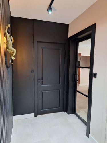 Un hall d'entrée noir et beige avec des lattes de bois et un verrière noire