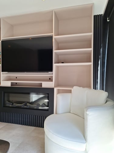 Zoom sur un mobilier sur-mesure beige avec des lattes de bois noires et un fauteuil blanc