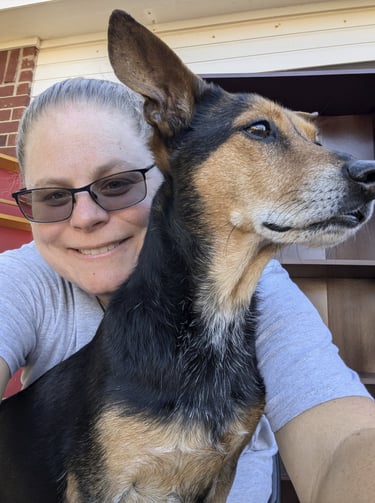 Laura Hooton on the left, in a grey tshirt, smiling, with a brown and black dog on the right.