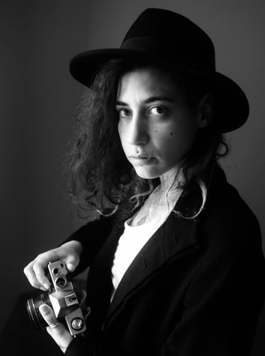 a woman photographe with a hat posing for a photo