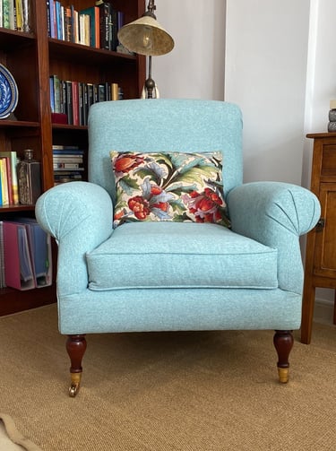 Sillón orejero tapizado en loneta azul celeste conservando patas con ruedas originales. Tenerife
