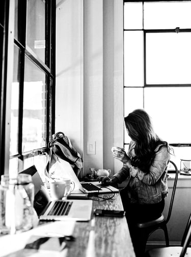 A woman works on a laptop at a cafe