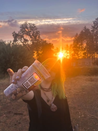 a woman with green hair holding a cup of rocks. by the sunset