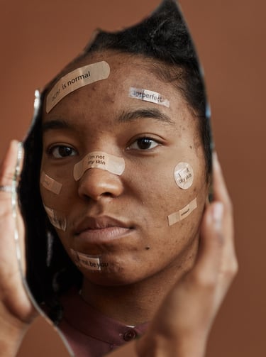 A young woman with acne and skin positive affirmations on her face looking in a broken mirror.