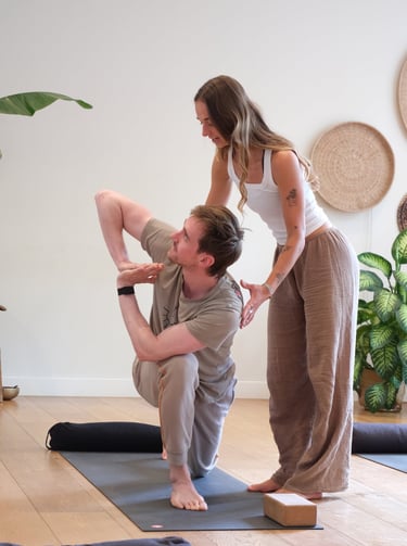 Jean adjusting a student in a yoga pose  in Leiden