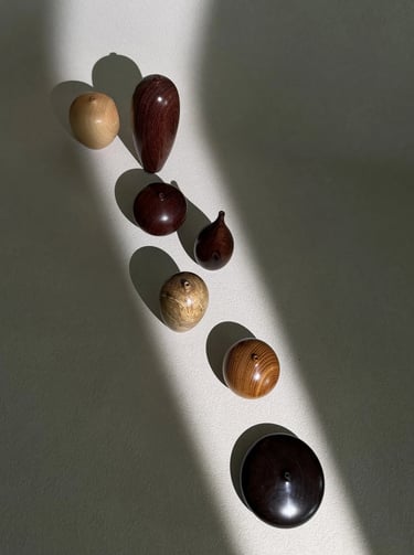 Handcrafted decorative wooden vessels in various wood grains and shapes displayed in a diagonal sunbeam.