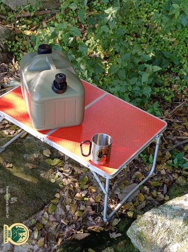 Mesa portátil de camping com o galão de água e a caneca de inox da HW Aventura