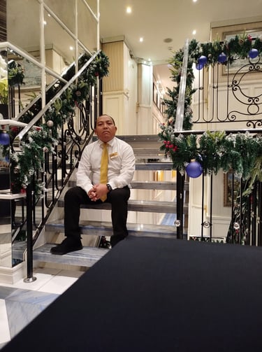 Balinese river crew in a formal uniform sitting on elegant stairs with Christmas decorations.