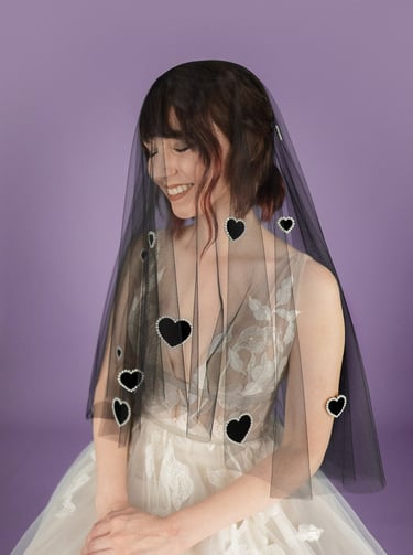 Bride wearing a black wedding veil with velvet hearts on it outlined in pearls