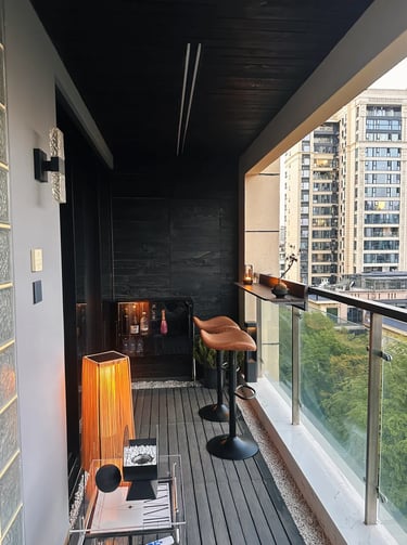 Cozy small balcony with space-saving furniture, soft cushions, potted plants, and warm evening light